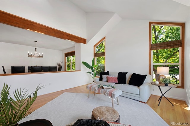 living room with vaulted ceiling with beams, light hardwood / wood-style flooring, and a chandelier