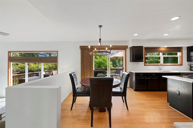 dining area with a healthy amount of sunlight, light hardwood / wood-style floors, sink, and a chandelier