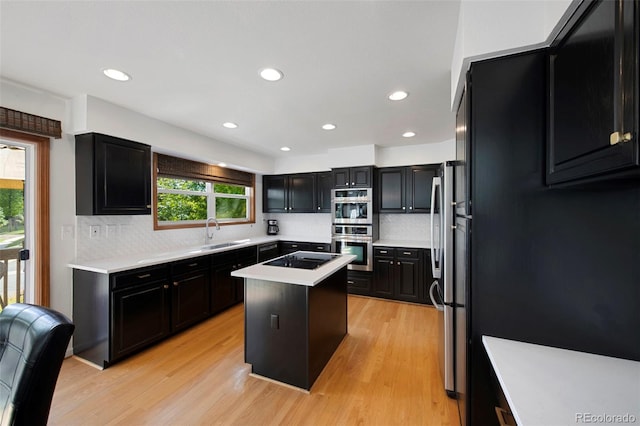 kitchen with decorative backsplash, light wood-type flooring, appliances with stainless steel finishes, and a kitchen island