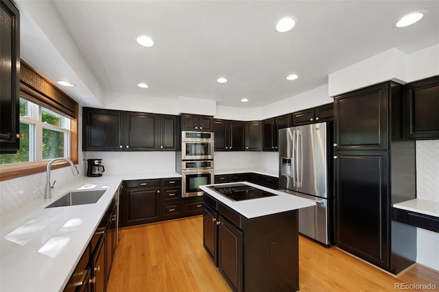 kitchen featuring light hardwood / wood-style floors, sink, a kitchen island, stainless steel appliances, and backsplash