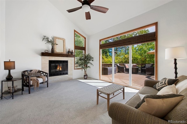 carpeted living room featuring a healthy amount of sunlight, a tiled fireplace, ceiling fan, and high vaulted ceiling