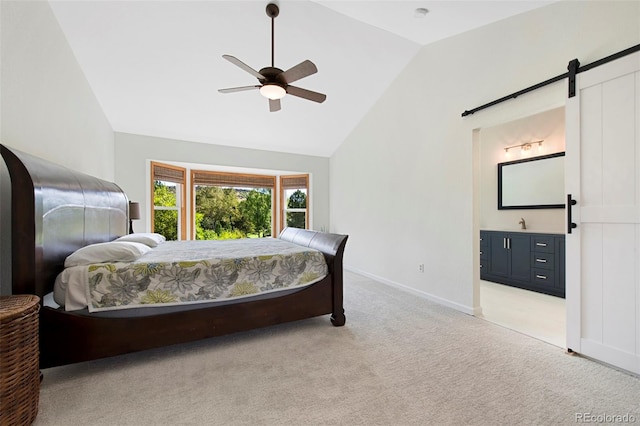 bedroom with vaulted ceiling, light colored carpet, a barn door, ensuite bath, and ceiling fan