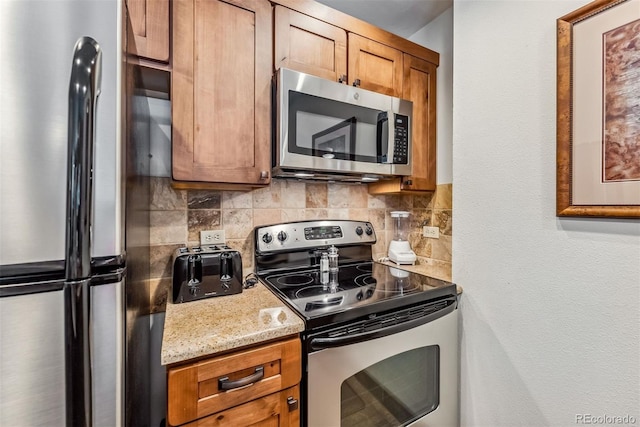 kitchen featuring appliances with stainless steel finishes, decorative backsplash, and light stone countertops