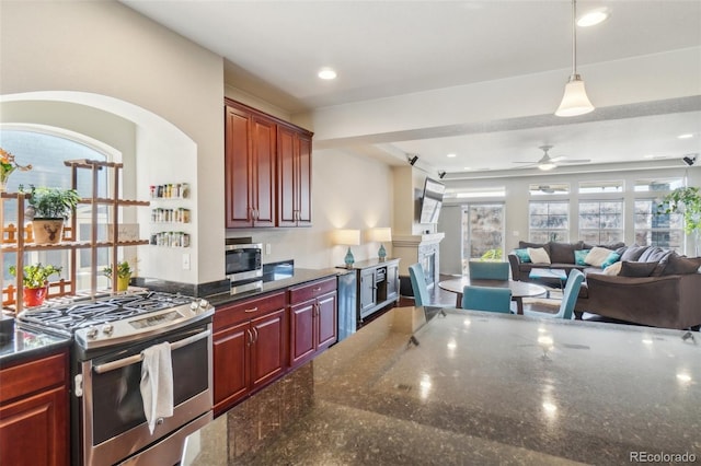 kitchen with ceiling fan, open floor plan, hanging light fixtures, appliances with stainless steel finishes, and reddish brown cabinets