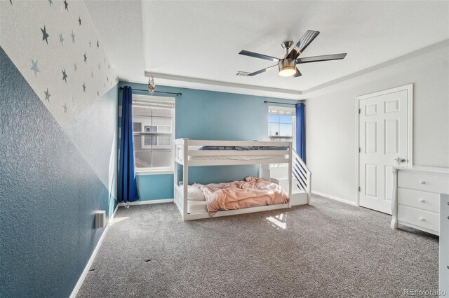 bedroom featuring visible vents, baseboards, a ceiling fan, a tray ceiling, and carpet floors