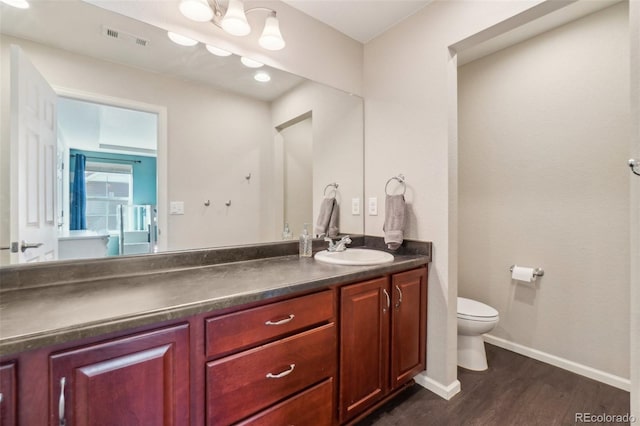 bathroom with baseboards, visible vents, toilet, wood finished floors, and vanity