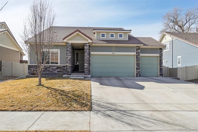 view of front of property featuring concrete driveway, a front yard, fence, a garage, and stone siding