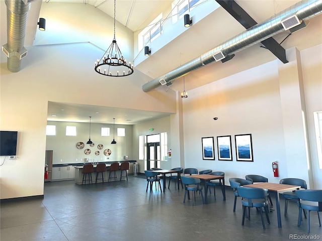 dining area featuring a towering ceiling, visible vents, and a chandelier