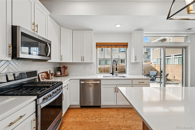 10123 Zeno St, Commerce City, CO 80022 - kitchen featuring appliances with stainless steel finishes, a sink, light wood finished floors, white cabinetry, and recessed lighting