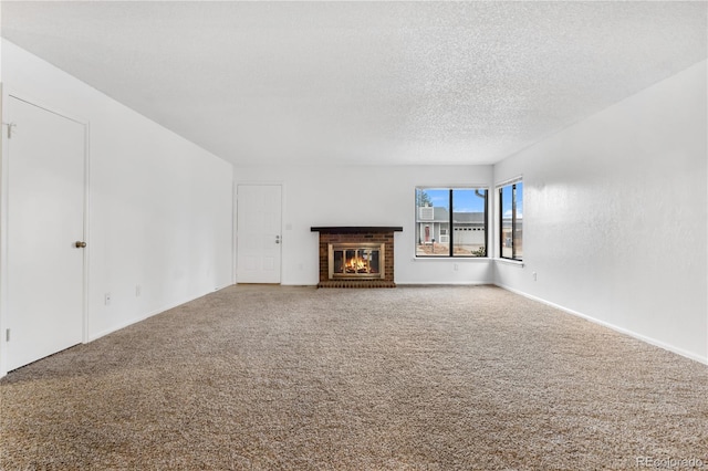 unfurnished living room featuring carpet floors, a textured ceiling, and a brick fireplace