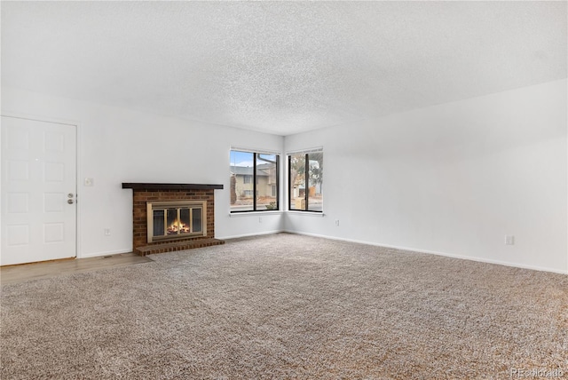 unfurnished living room with carpet flooring, a textured ceiling, and a brick fireplace