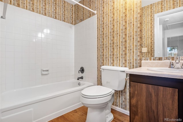 full bathroom featuring hardwood / wood-style floors, vanity, tiled shower / bath combo, and toilet