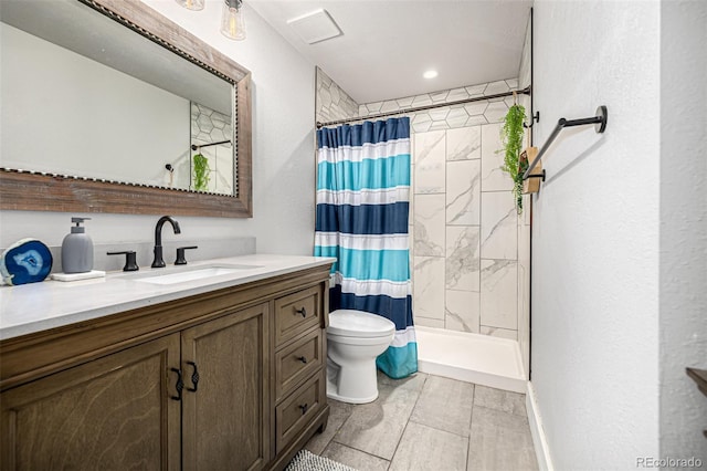 bathroom with tiled shower, vanity, and toilet