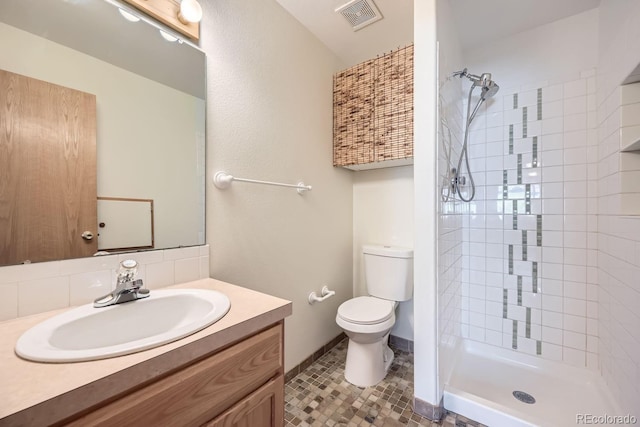 bathroom with tile patterned flooring, a tile shower, vanity, and toilet