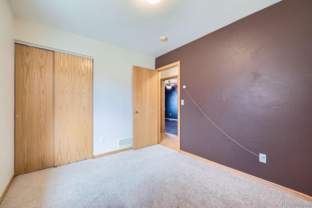 unfurnished bedroom with light carpet and a closet