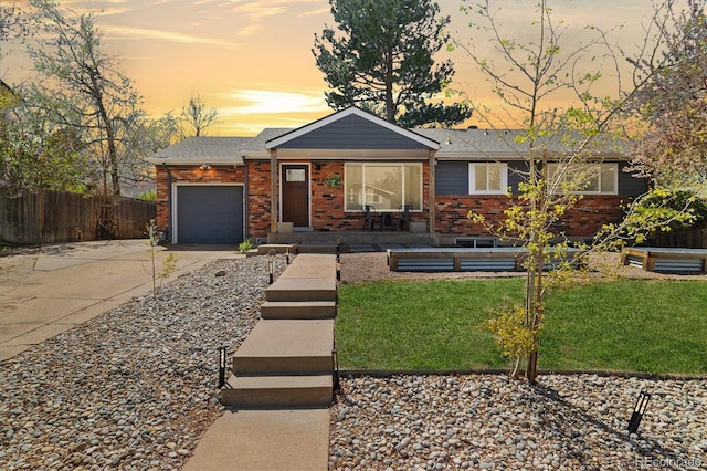 view of front facade with fence, brick siding, a garage, a front yard, and driveway