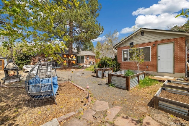 882 E Briarwood Cir, Centennial, CO 80122 - exterior space featuring brick siding, a fire pit, and a vegetable garden