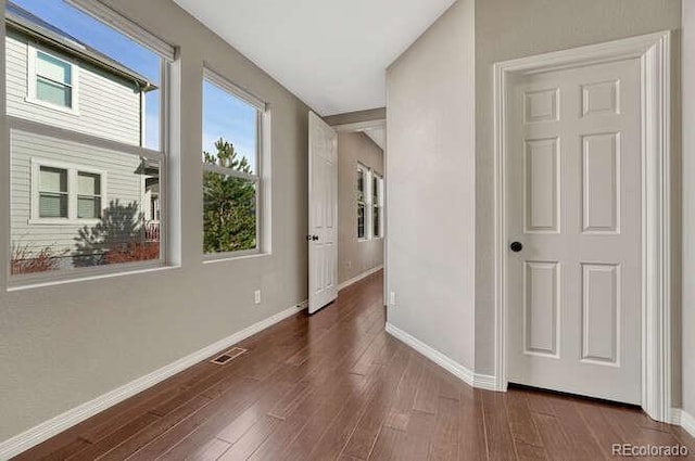 corridor featuring visible vents, baseboards, and wood finished floors