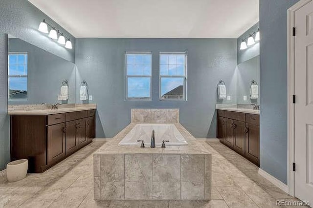 bathroom with a sink, two vanities, and a bath