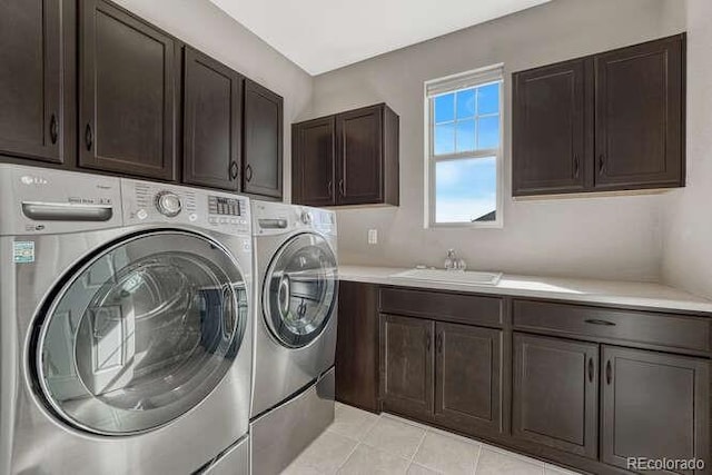 laundry room with a sink, light tile patterned floors, cabinet space, and washing machine and clothes dryer