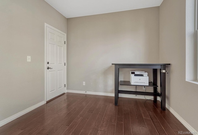 spare room featuring baseboards and dark wood-style flooring