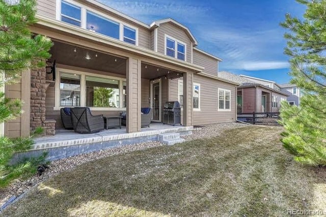 back of property with stone siding and a patio area