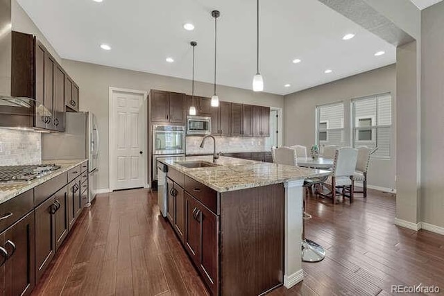 kitchen with dark wood-style flooring, a sink, dark brown cabinetry, appliances with stainless steel finishes, and decorative light fixtures