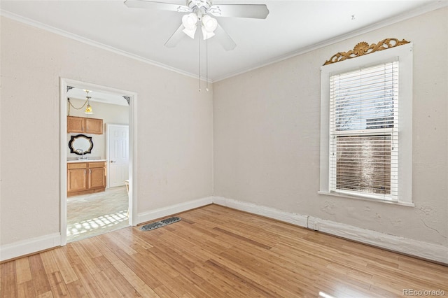 empty room featuring ceiling fan, ornamental molding, and light wood-type flooring