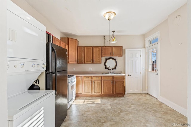 kitchen featuring black fridge, sink, gas range gas stove, decorative light fixtures, and stacked washer / dryer