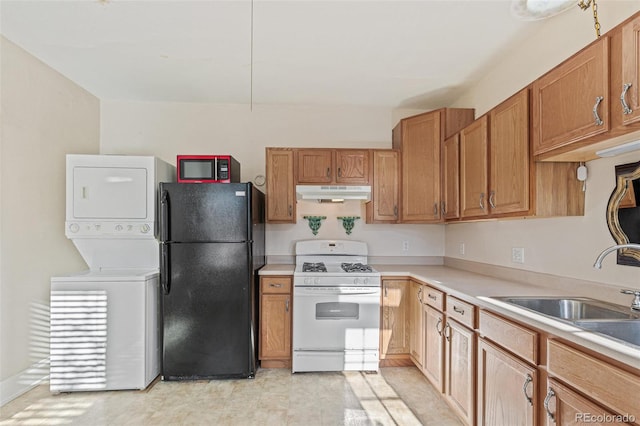 kitchen with black appliances, sink, and stacked washer / dryer