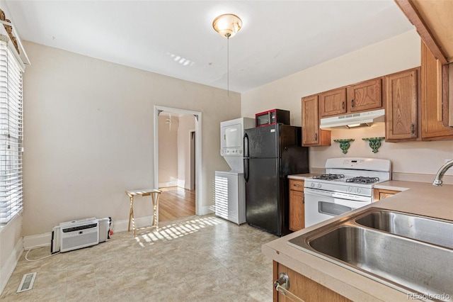 kitchen featuring black refrigerator, an AC wall unit, white gas stove, and sink