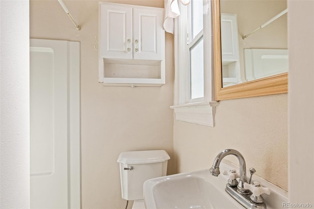 bathroom with toilet, sink, and walk in shower