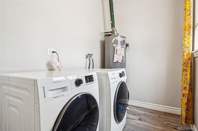 clothes washing area featuring washer and dryer, electric water heater, wood finished floors, baseboards, and laundry area