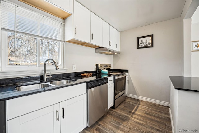 kitchen with dark wood-style floors, a sink, white cabinets, appliances with stainless steel finishes, and dark countertops