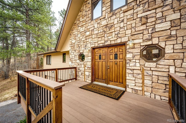 doorway to property featuring stone siding and a wooden deck
