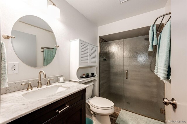 bathroom featuring toilet, a stall shower, and vanity