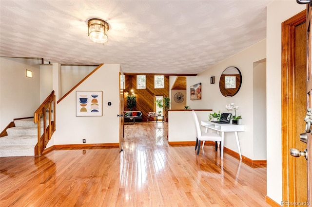 foyer entrance featuring stairs, light wood-type flooring, baseboards, and a textured ceiling