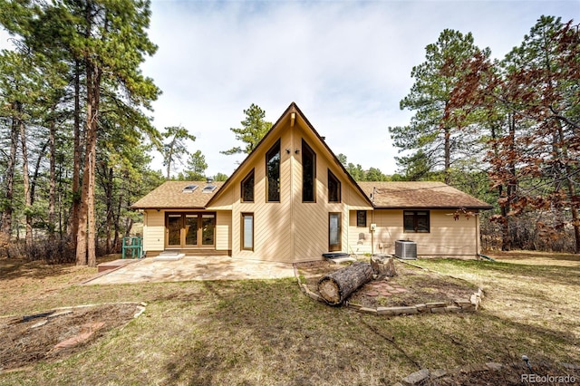 rear view of property with a patio area, central AC, a shingled roof, and a lawn
