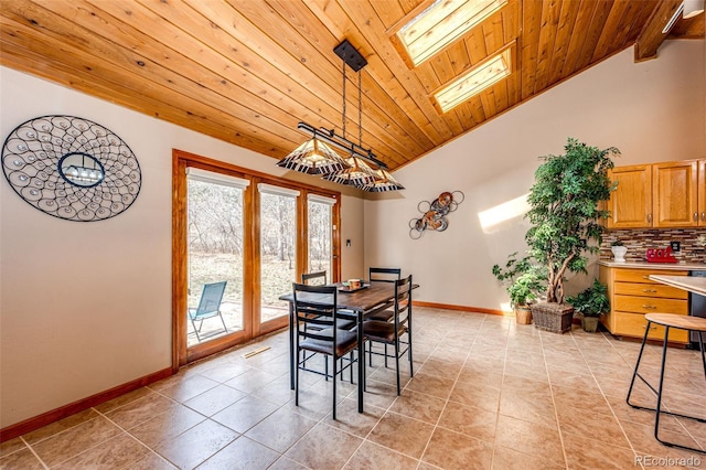 dining space featuring light tile patterned flooring, baseboards, wooden ceiling, and a skylight