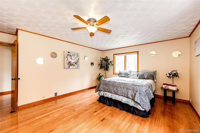 bedroom featuring baseboards, ornamental molding, a ceiling fan, a textured ceiling, and wood finished floors