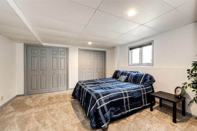 bedroom featuring a paneled ceiling, baseboards, recessed lighting, two closets, and carpet