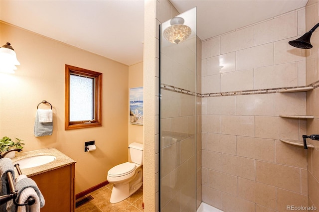 full bath featuring vanity, baseboards, toilet, tiled shower, and visible vents