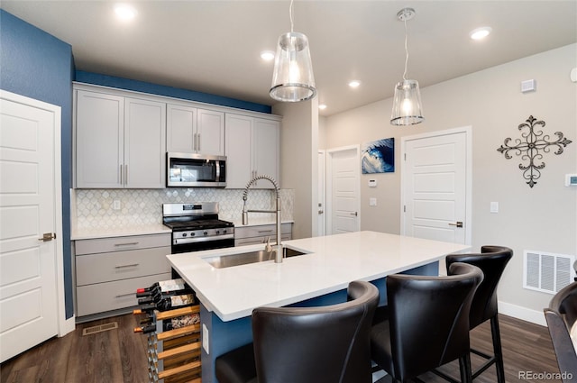 9804 Rosalee Peak St, Littleton, CO 80125 - kitchen featuring appliances with stainless steel finishes, dark wood finished floors, decorative backsplash, light countertops, and a breakfast bar