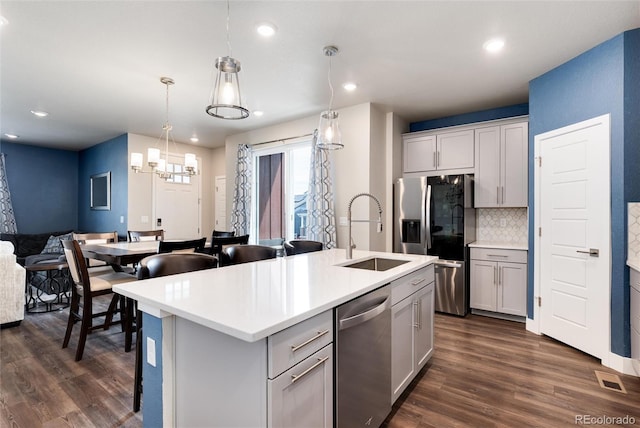 9804 Rosalee Peak St, Littleton, CO 80125 - kitchen with stainless steel appliances, a sink, open floor plan, dark wood finished floors, and backsplash