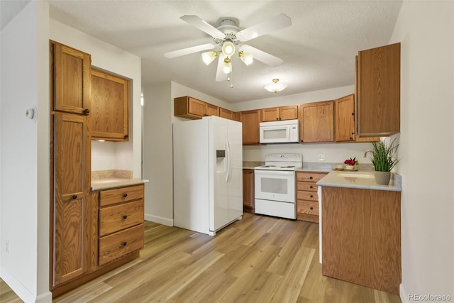 13606 E Bates Ave Unit 304, Aurora, CO 80014 - kitchen with white appliances, light wood finished floors, brown cabinets, light countertops, and a ceiling fan