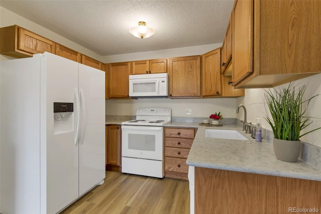 13606 E Bates Ave Unit 304, Aurora, CO 80014 - kitchen featuring white appliances, a sink, light wood finished floors, brown cabinetry, and a textured ceiling