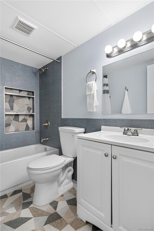 2281 Vaughn Unit 104A, Aurora, CO 80014 - bathroom featuring toilet, vanity, shower / bathtub combination, and tile walls