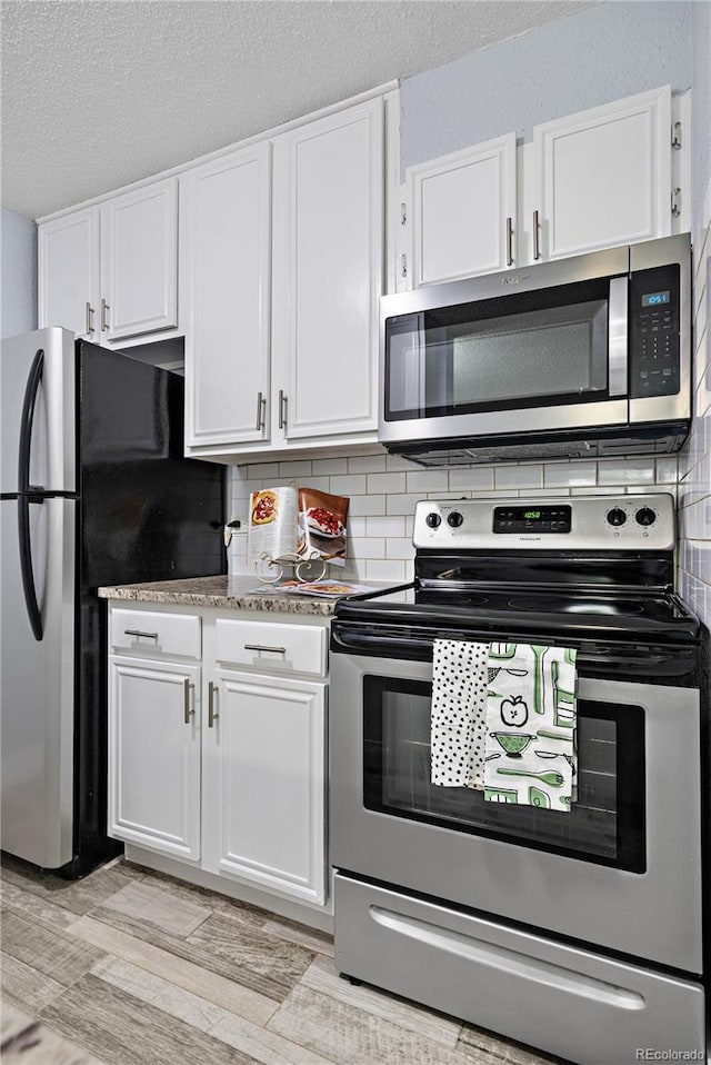 2281 Vaughn Unit 104A, Aurora, CO 80014 - kitchen featuring stainless steel appliances, white cabinets, decorative backsplash, and a textured ceiling