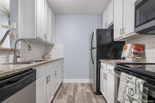 2281 Vaughn Unit 104A, Aurora, CO 80014 - kitchen with stainless steel appliances, a sink, light wood-style flooring, backsplash, and white cabinets