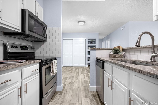 2281 Vaughn Unit 104A, Aurora, CO 80014 - kitchen featuring stainless steel appliances, a sink, light wood-style flooring, a textured ceiling, and decorative backsplash